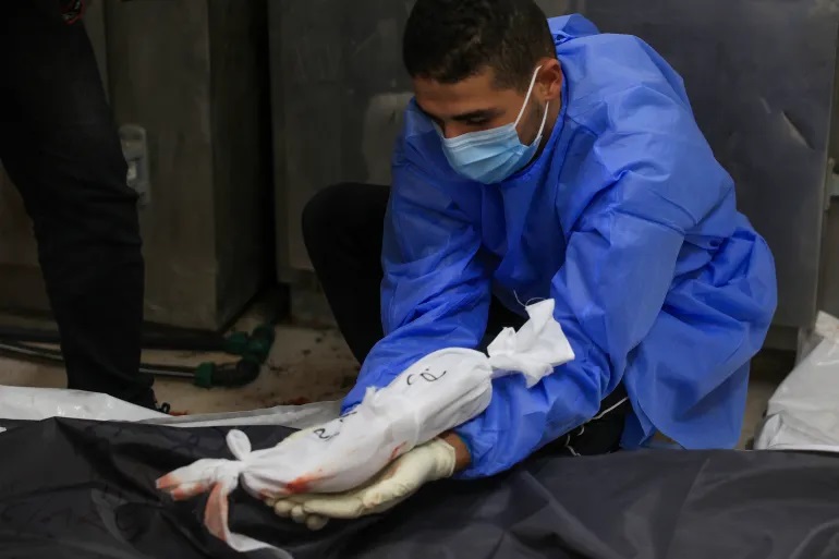 جنين مكفّن يوضع بجوار جثمان أمه بعد استشهادهما بقصف إسرائيلي (الفرنسية)